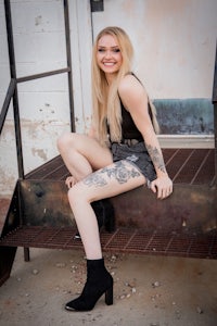 a young woman with tattoos sitting on the steps of a building